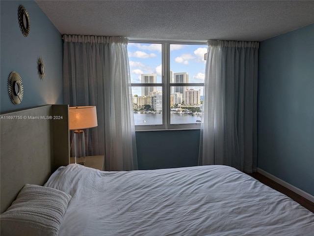 bedroom with a textured ceiling and a water view