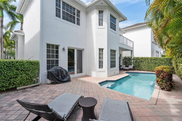 rear view of house featuring a fenced in pool, pool water feature, and a patio