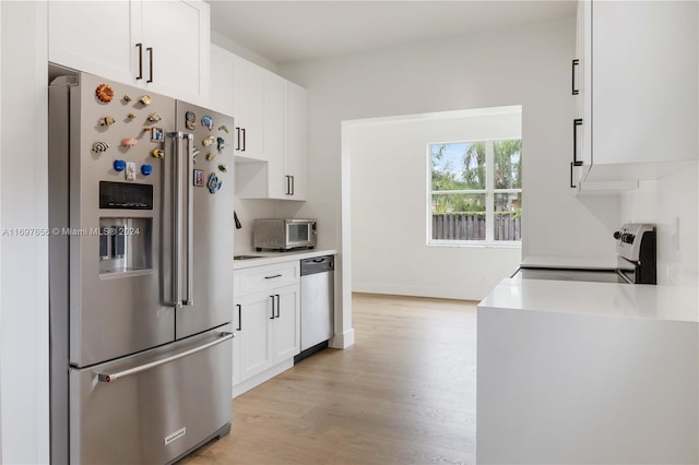 kitchen with light hardwood / wood-style flooring, white cabinets, and appliances with stainless steel finishes