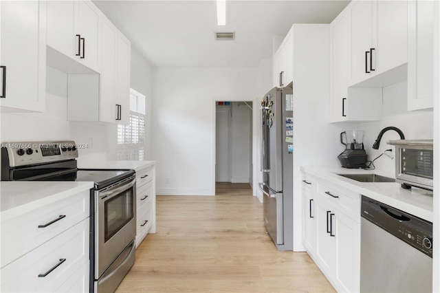 kitchen featuring white cabinetry, sink, stainless steel appliances, and light hardwood / wood-style floors