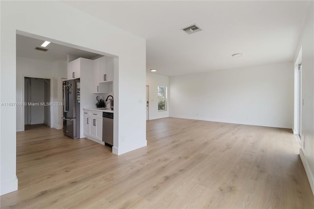 unfurnished living room with light wood-type flooring and sink