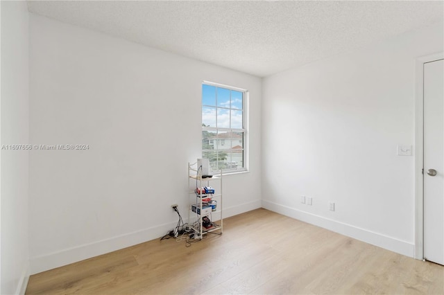 unfurnished room with hardwood / wood-style floors and a textured ceiling