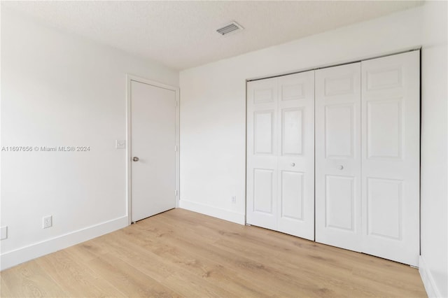 unfurnished bedroom featuring a closet, light hardwood / wood-style floors, and a textured ceiling