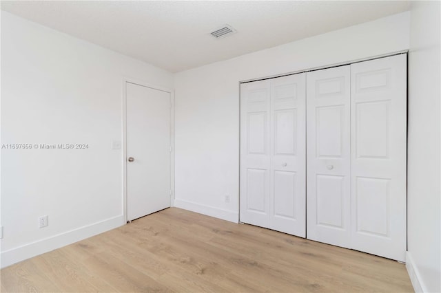 unfurnished bedroom with light hardwood / wood-style floors and a closet