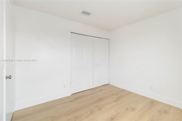 unfurnished bedroom with a closet and light wood-type flooring