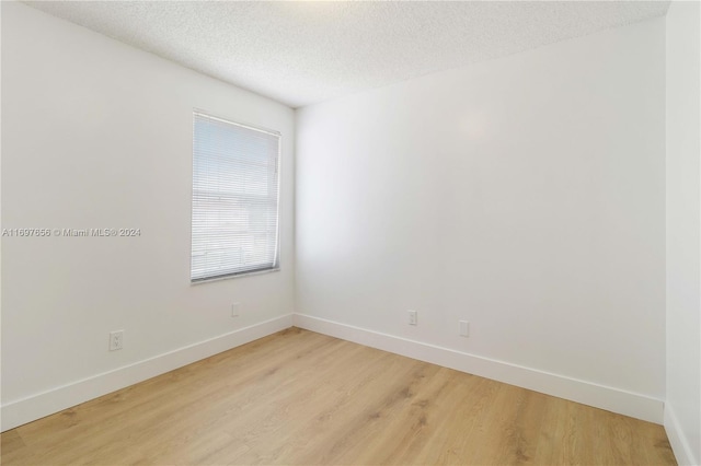 unfurnished room with a textured ceiling and light hardwood / wood-style flooring