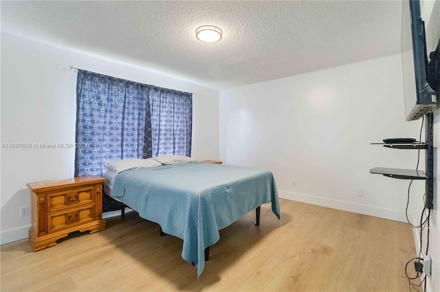 bedroom featuring light wood-type flooring and a textured ceiling