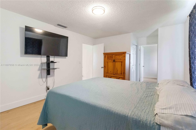 bedroom with a textured ceiling and light hardwood / wood-style flooring