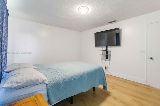 bedroom featuring hardwood / wood-style floors and a textured ceiling