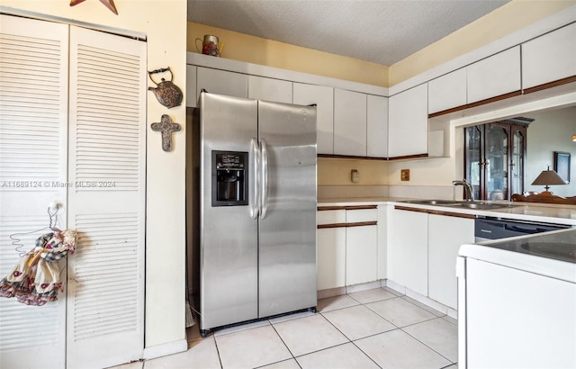 kitchen featuring sink, stainless steel fridge, light tile patterned floors, a textured ceiling, and white cabinetry