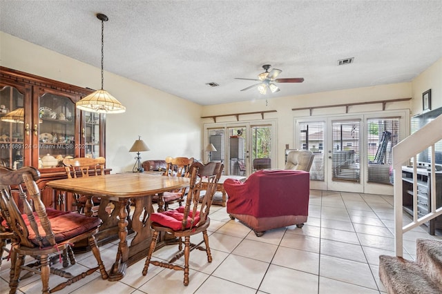 tiled dining room with a textured ceiling and ceiling fan