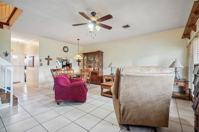 living room featuring ceiling fan, light tile patterned floors, and a textured ceiling