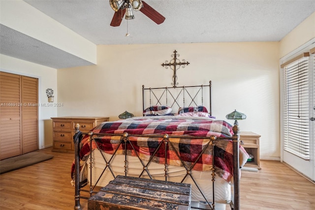 bedroom with a textured ceiling, light wood-type flooring, a closet, and ceiling fan