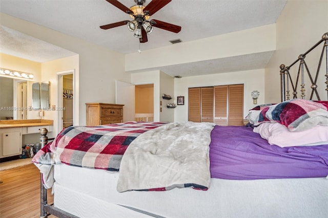 bedroom with ensuite bath, ceiling fan, a textured ceiling, light hardwood / wood-style floors, and a closet