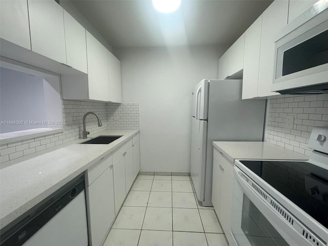 kitchen with white cabinets, white appliances, light tile patterned flooring, and sink