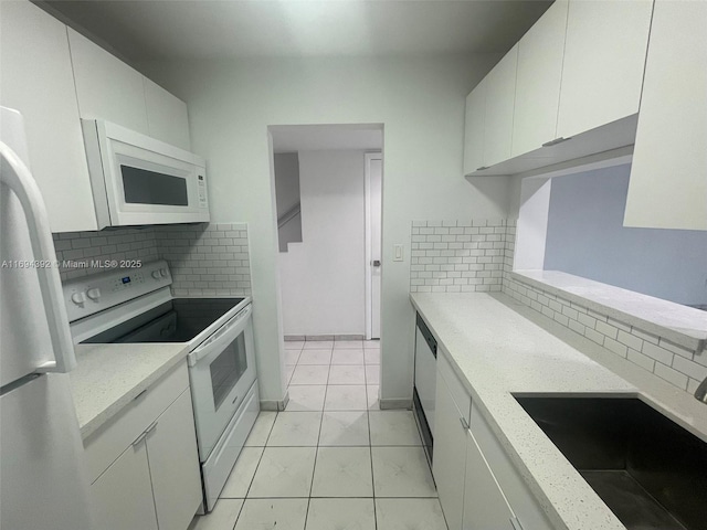 kitchen featuring sink, light stone counters, backsplash, white appliances, and white cabinets