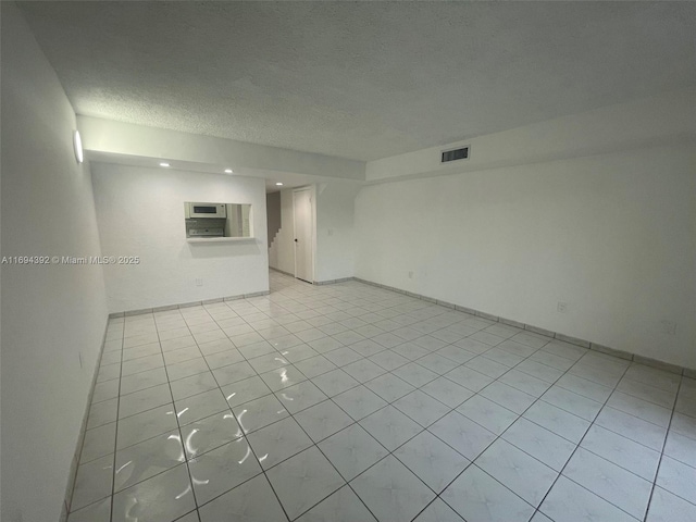 tiled empty room with a textured ceiling