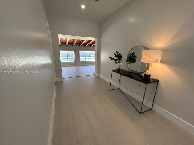 hall with beamed ceiling and light hardwood / wood-style flooring