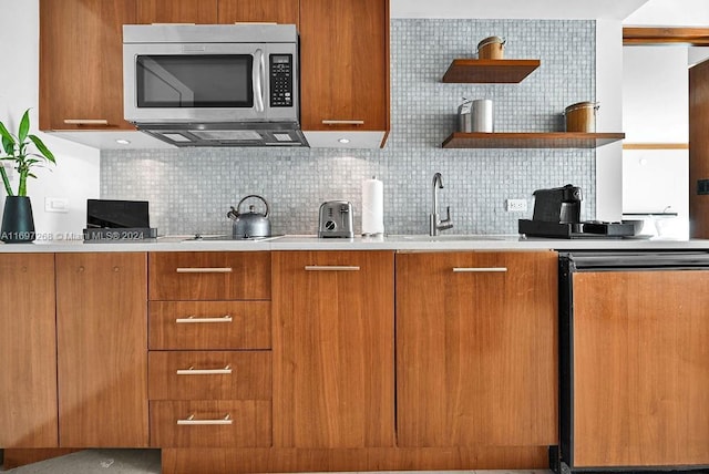 kitchen featuring decorative backsplash, black stovetop, dishwashing machine, and sink