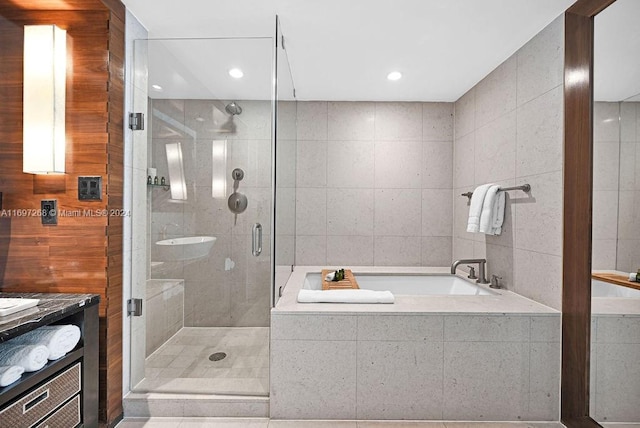 bathroom featuring shower with separate bathtub, vanity, tile patterned floors, and tile walls