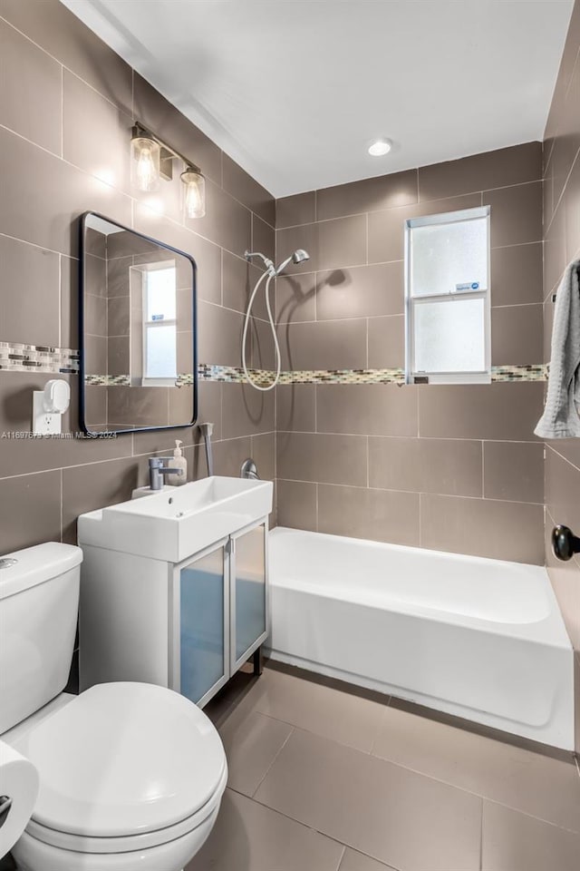 full bathroom with vanity, tile patterned flooring, tiled shower / bath combo, toilet, and tile walls