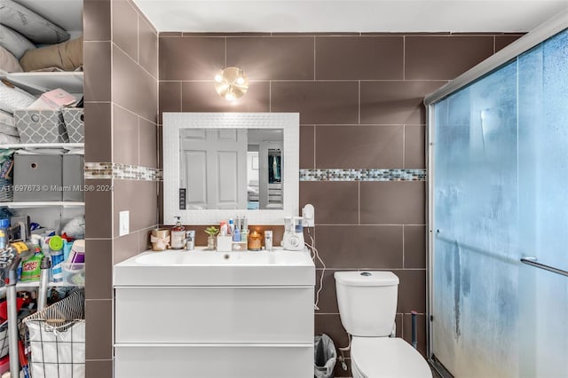 bathroom featuring vanity, toilet, and tile walls