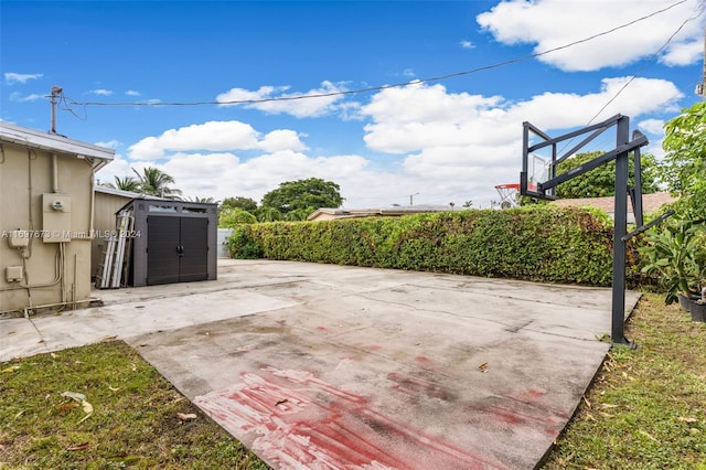 view of patio / terrace featuring basketball court and a storage unit