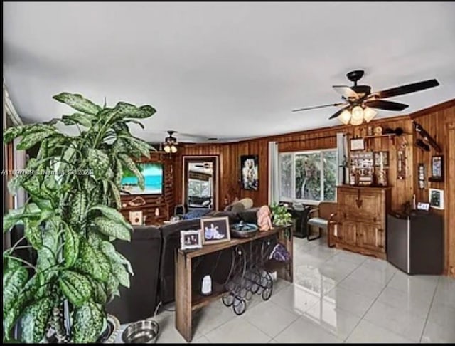 tiled living room with ceiling fan and wood walls