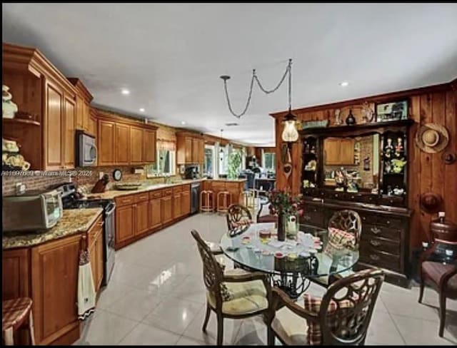 kitchen featuring kitchen peninsula, pendant lighting, stainless steel appliances, and light tile patterned flooring