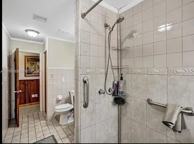 bathroom featuring a shower with door, tile patterned floors, crown molding, toilet, and tile walls