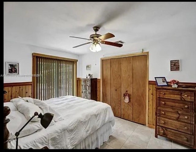 bedroom with light tile patterned floors, ceiling fan, and wooden walls