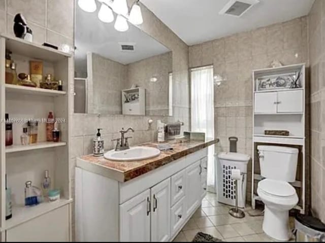 bathroom featuring tile patterned flooring, vanity, tile walls, and toilet