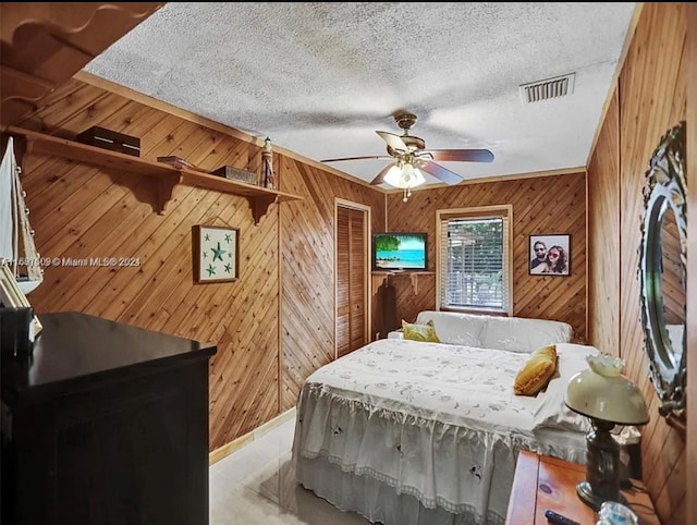 bedroom featuring ceiling fan, a textured ceiling, and wooden walls