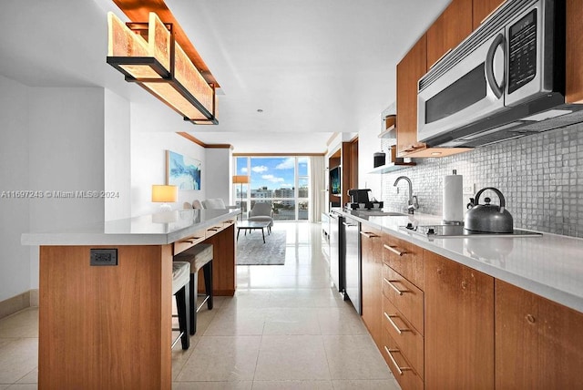 kitchen featuring floor to ceiling windows, sink, decorative backsplash, light tile patterned flooring, and appliances with stainless steel finishes