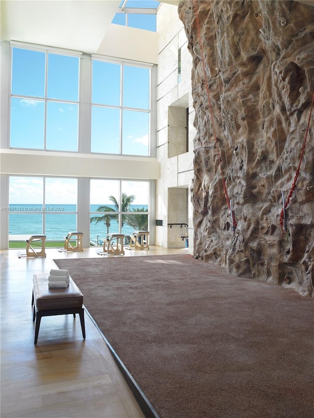 unfurnished living room featuring hardwood / wood-style floors, a water view, and a towering ceiling