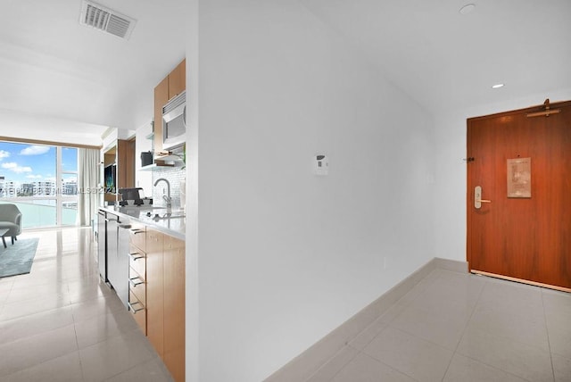 hallway featuring light tile patterned flooring, sink, and floor to ceiling windows