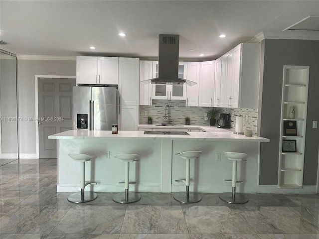 kitchen featuring stainless steel refrigerator with ice dispenser, white cabinetry, island range hood, kitchen peninsula, and a breakfast bar area