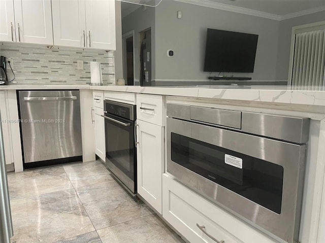 kitchen with white cabinets, tasteful backsplash, stainless steel dishwasher, and ornamental molding