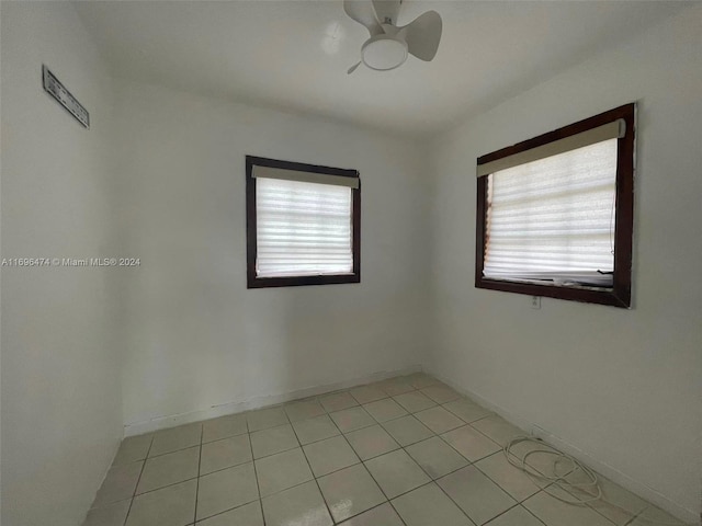 empty room with ceiling fan, plenty of natural light, and light tile patterned flooring