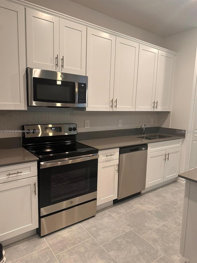 kitchen featuring white cabinets, sink, light tile patterned floors, tasteful backsplash, and stainless steel appliances