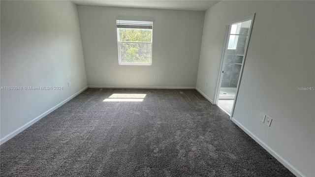 spare room with dark colored carpet