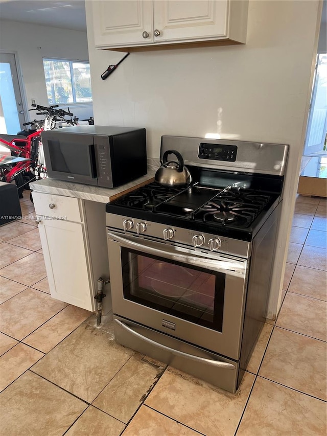 kitchen featuring appliances with stainless steel finishes, white cabinetry, and light tile patterned flooring