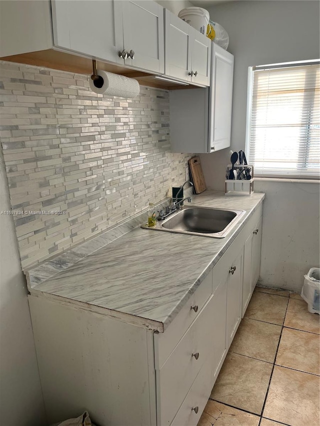 kitchen featuring white cabinets, light tile patterned floors, sink, and tasteful backsplash