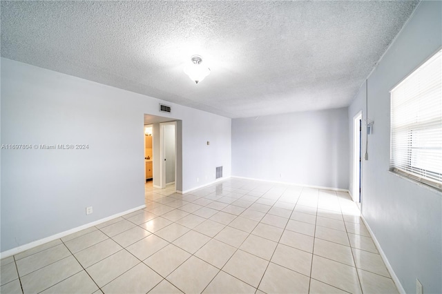 spare room with a textured ceiling and light tile patterned flooring