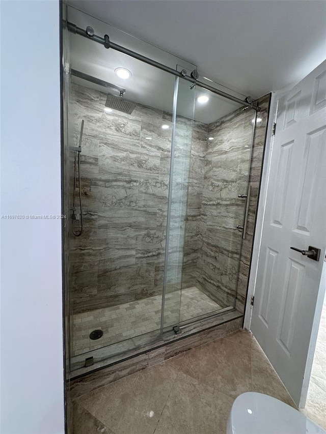 bathroom featuring toilet, tile patterned floors, and a shower with shower door