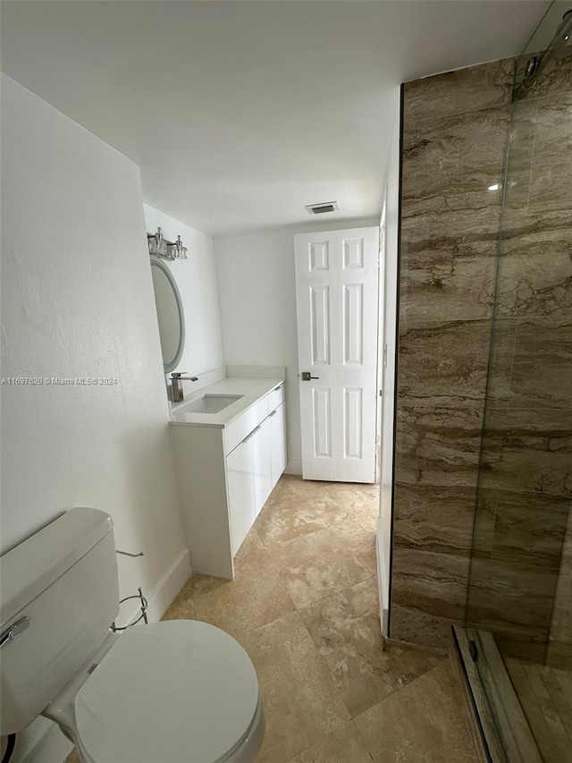 bathroom featuring a tile shower, vanity, and toilet