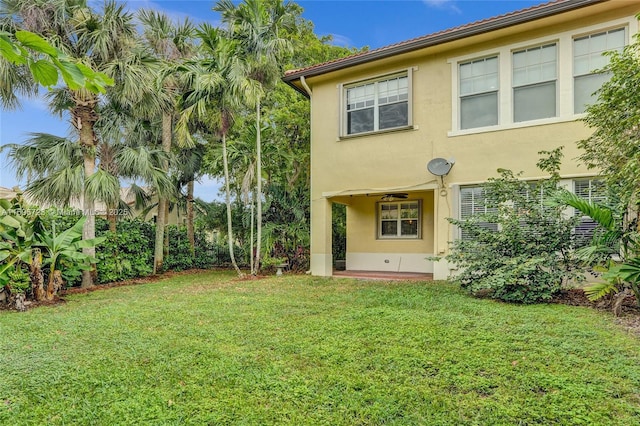 rear view of property featuring ceiling fan, a patio area, and a yard