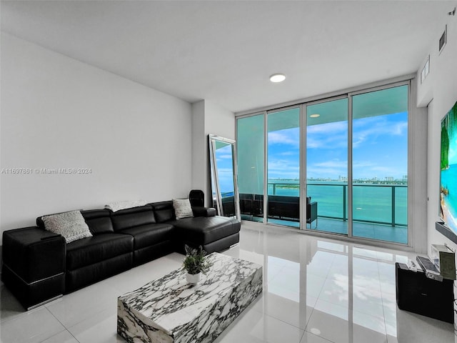 tiled living room featuring expansive windows, plenty of natural light, and a water view