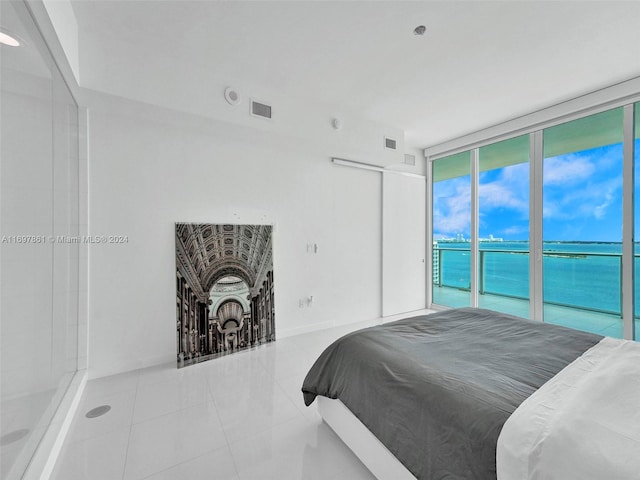 tiled bedroom featuring expansive windows, a water view, and access to outside