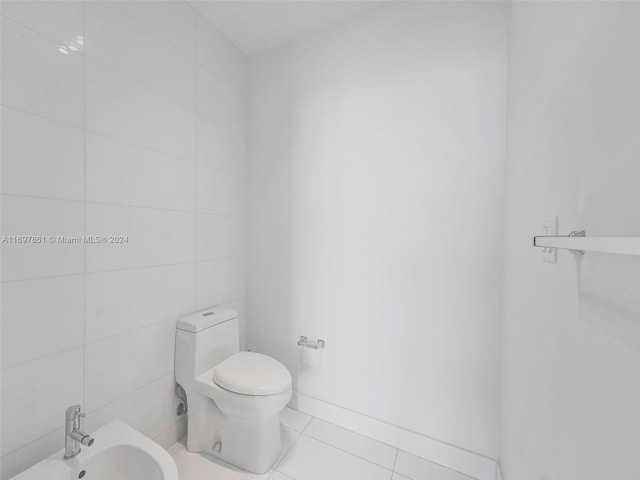 bathroom with tile patterned flooring, a bidet, tile walls, and toilet